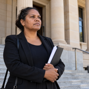 Illustration of an unidentified woman holding documents outside a courthouse.